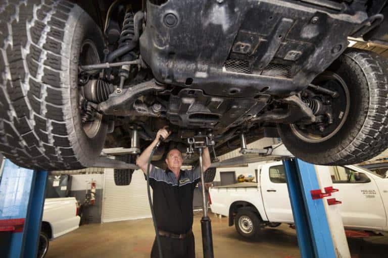 professional car mechanic working under car that is on a lift in auto adrian's balcatta car care centre