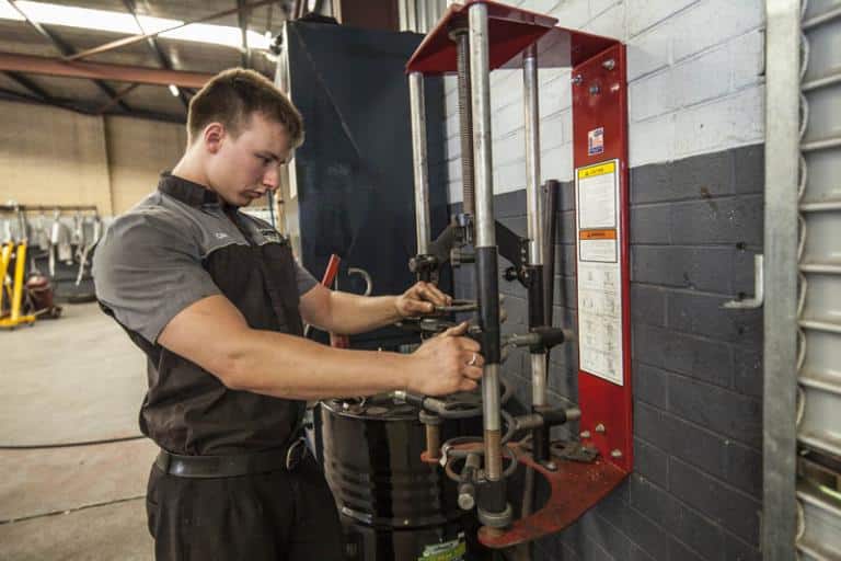 auto mechanic repairing vehicle coil suspension in machine