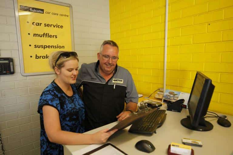 man and women going over the bookings for the day in the reception area at adrian's balcatta car care centre