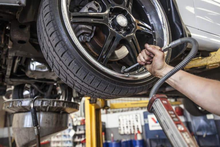 mechanic testing a tire's pressure while car is on the lift