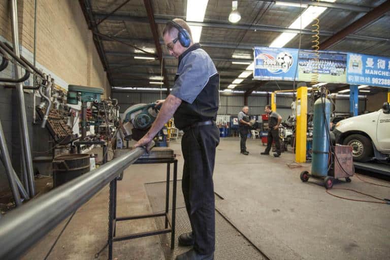 auto mechanic cuts metal with a metal grinding machine in the car servicing workshop